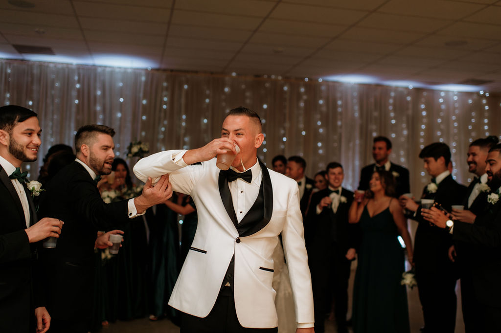 Groom taking a drink at the reception