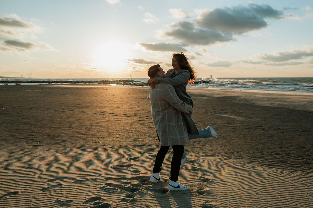 Couple posing for photos on a beach in MI during sunset