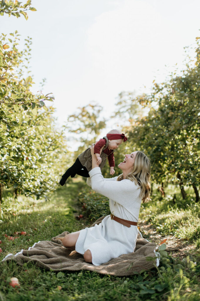 Mother holding her daughter for photos at an apple orchard