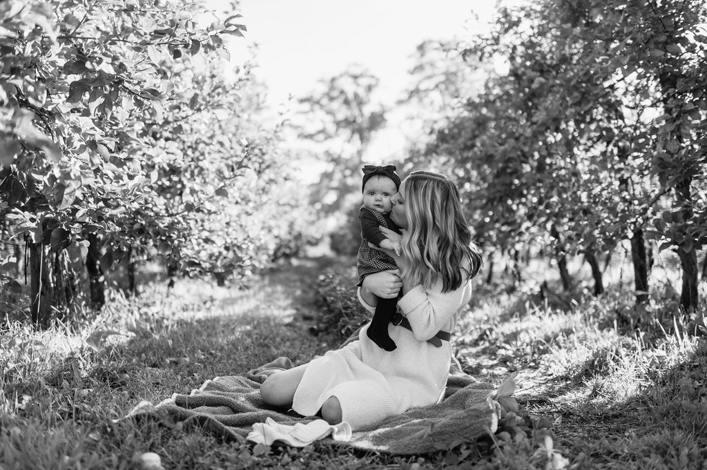 Mother kissing her daughter for photos at an apple orchard