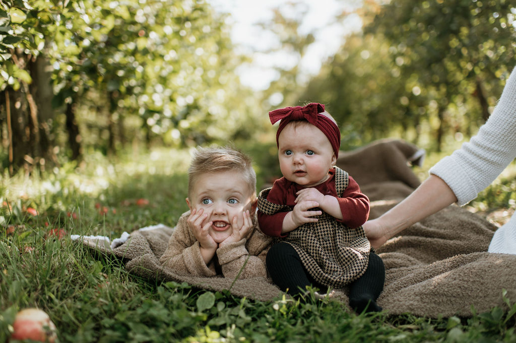 Brother and sister posing for photos in an apple field