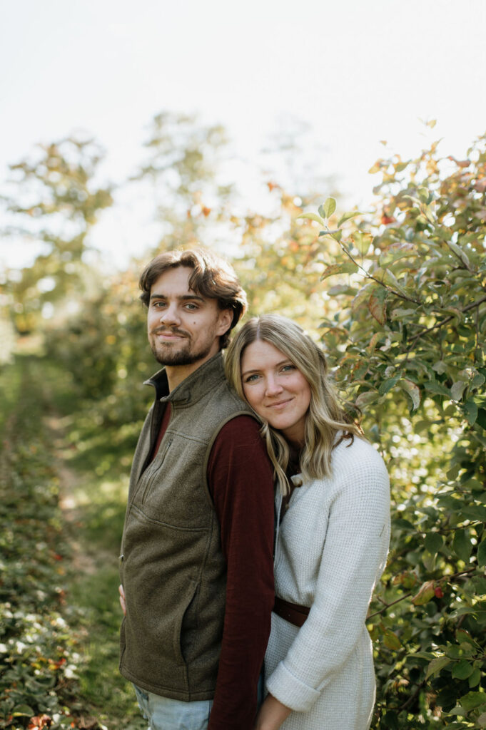 Man and woman posing for photos in an apple orchard