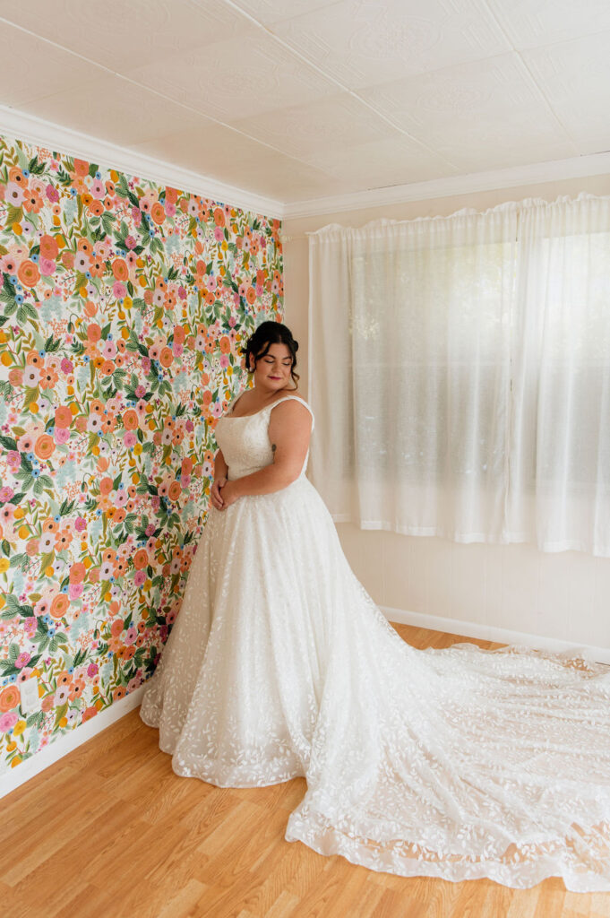 Bride posing at her home with colorful floral wallpaper