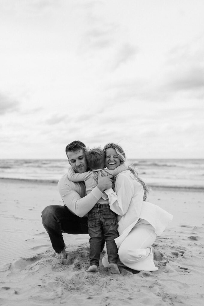 Toddler hugging his parents on the beach at Indiana Dunes National Park