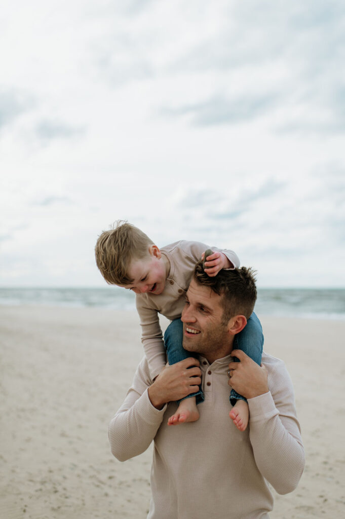 Man with his toddler son on his shoulders at the beach