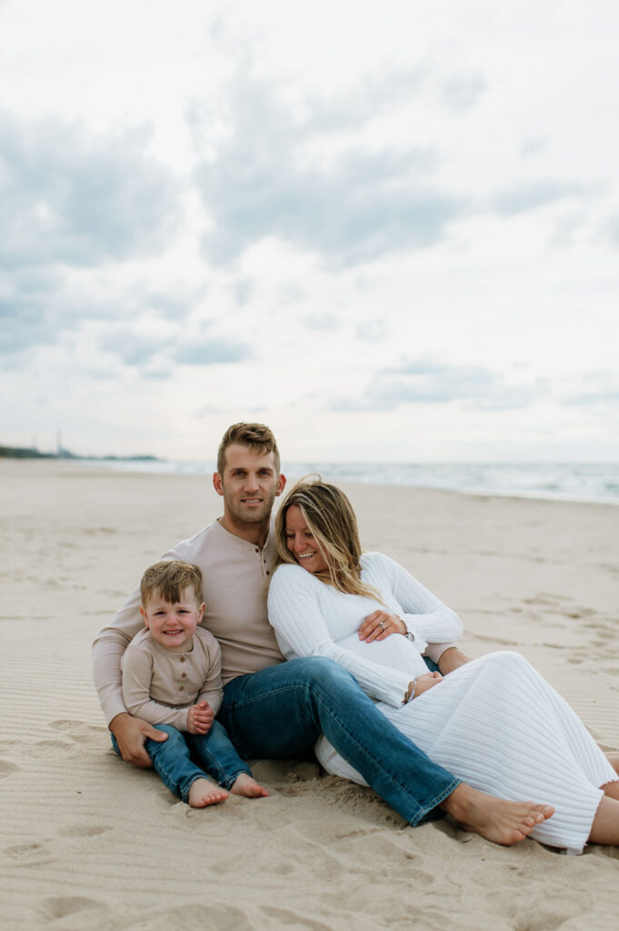 Family sitting on the beach at Indiana Dunes National Park for their family maternity photoshoot