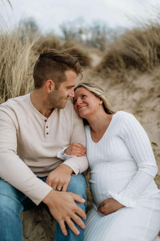 Pregnant woman smiling at her husband while sitting on the beach