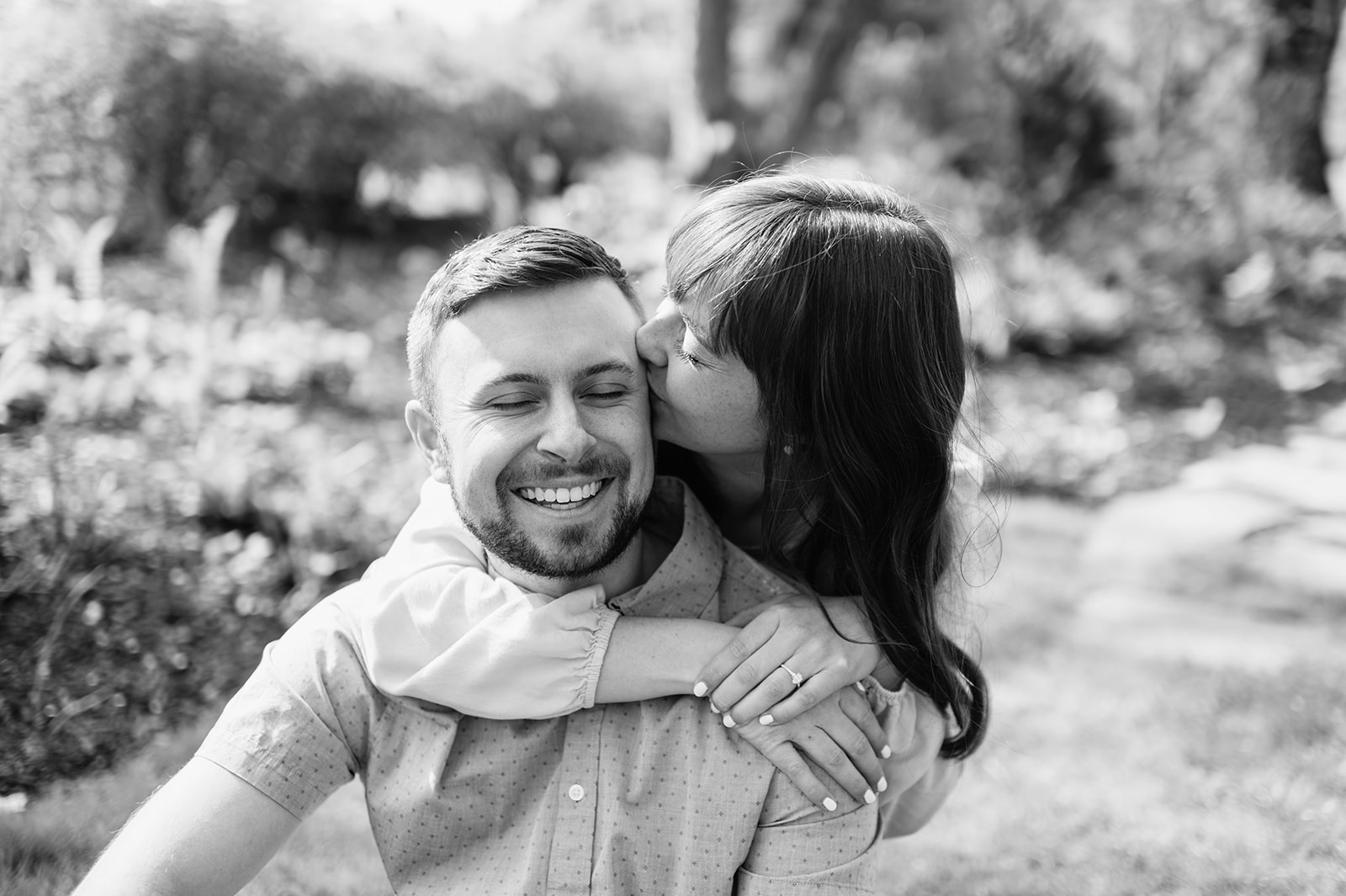 Black and white photo of a woman kissing her fiancé for during their engagement session