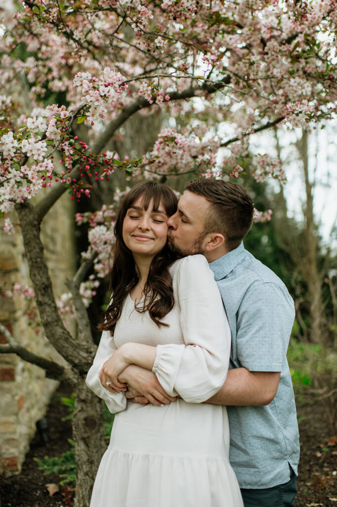Couple posing for photos near a blossom tree