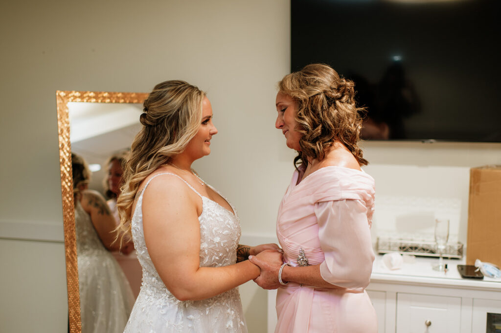 Bride and her mother holding hands as they get ready for the wedding