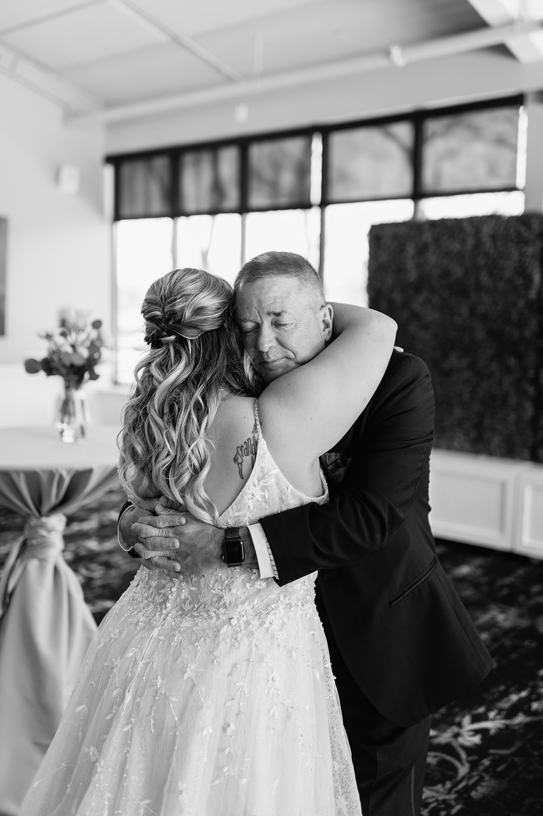 Black and white photo of a bride and her father hugging during their first looks