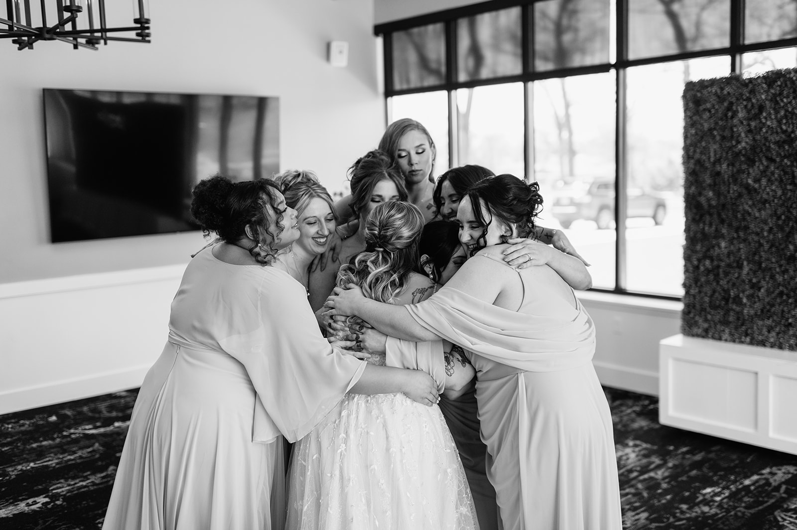 Black and white photo of a bride hugging her bridesmaids after sharing a first look