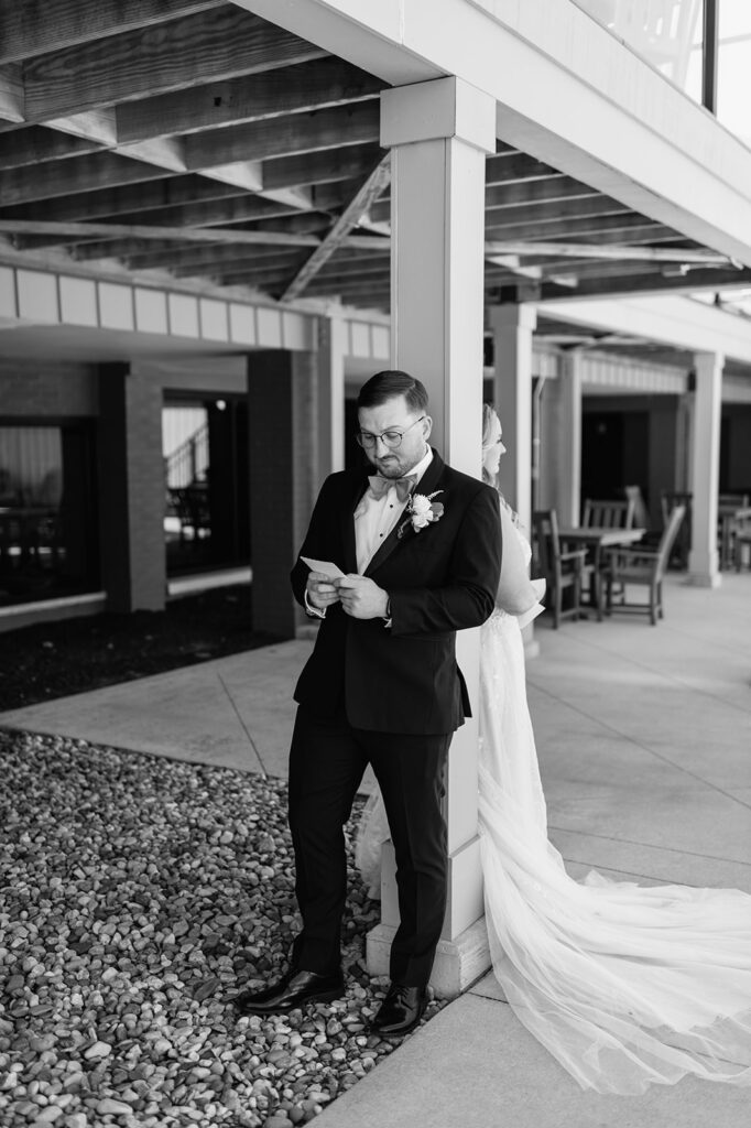 Black and white photo of a groom reading private vows to his bride during their first touch from their Morris Park Country Club wedding in South Bend, Indiana