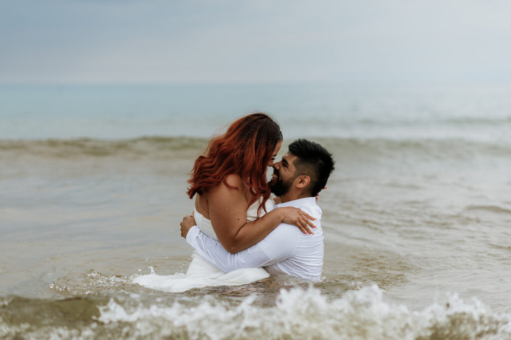 Bride and groom being playful as they dip into Lake Michigan from their elopement in Indiana at Indiana Dunes National Park