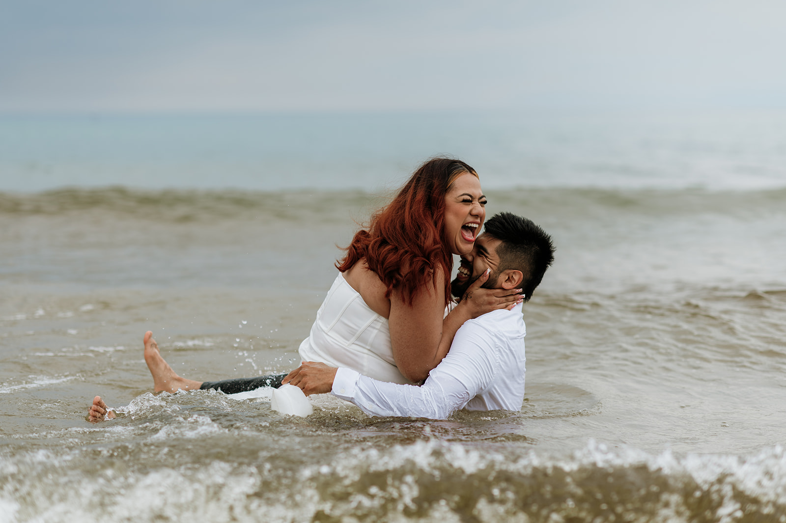 Bride and groom being playful as they dip into Lake Michigan from their elopement in Indiana at Indiana Dunes National Park