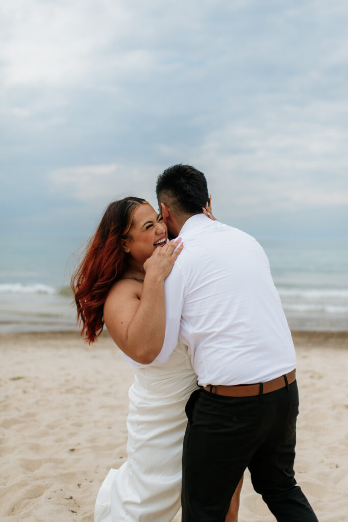 Bride and groom being playful on the beach for their elopement in Indiana at Indiana Dunes National Park