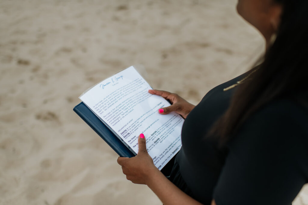 Officiant reading vows to bride and groom during an intimate beach ceremony