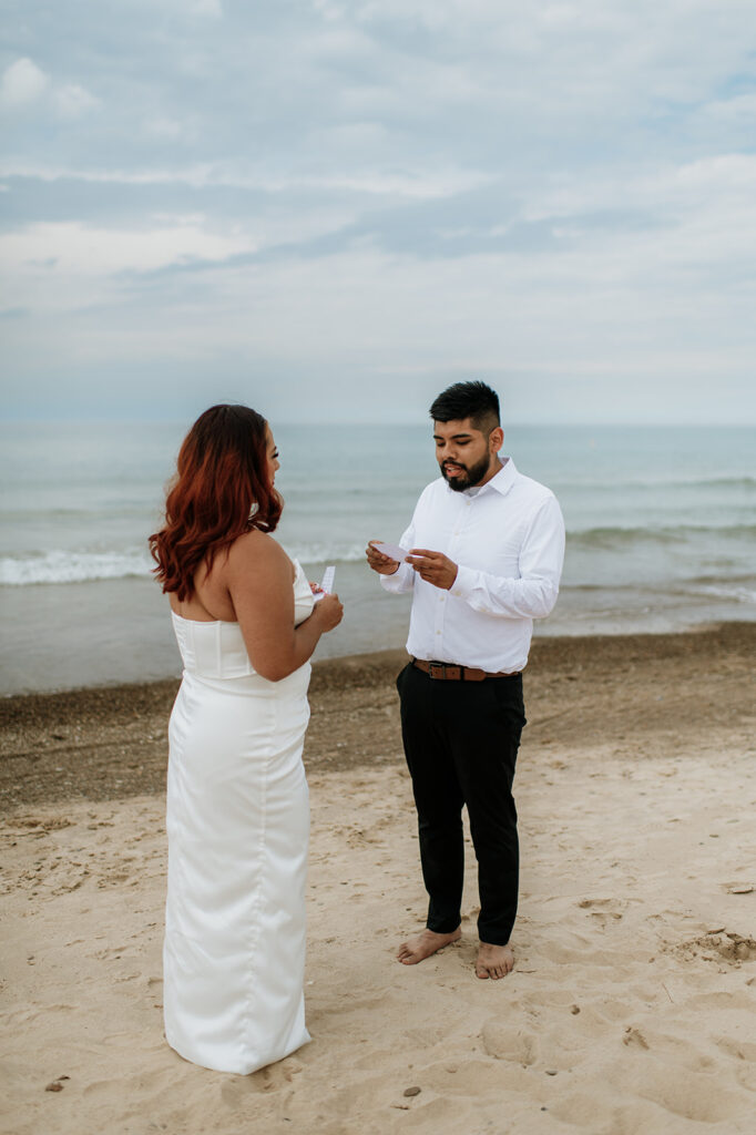 Groom reading his vows to his bride on the beach