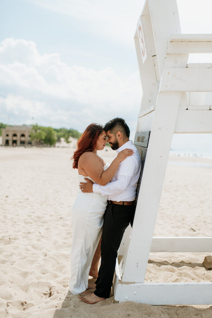 Bride and groom leaning against a lifeguards watch tower at Indiana Dunes National Park