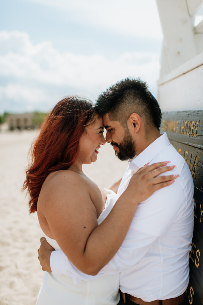 Bride and groom leaning against a lifeguards watch tower at Indiana Dunes National Park