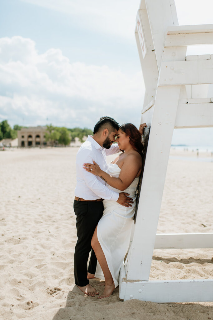 Bride and groom leaning against a lifeguard watch stand at Indiana Dunes National Park