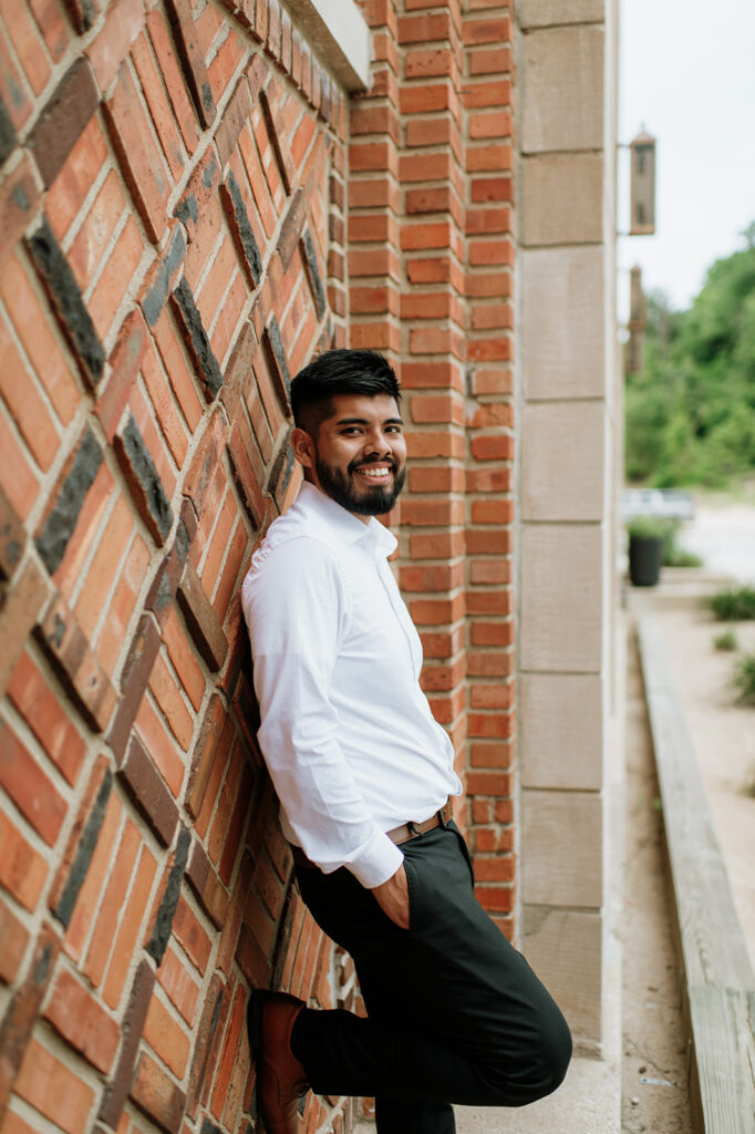 Groom leaning against a brick wall