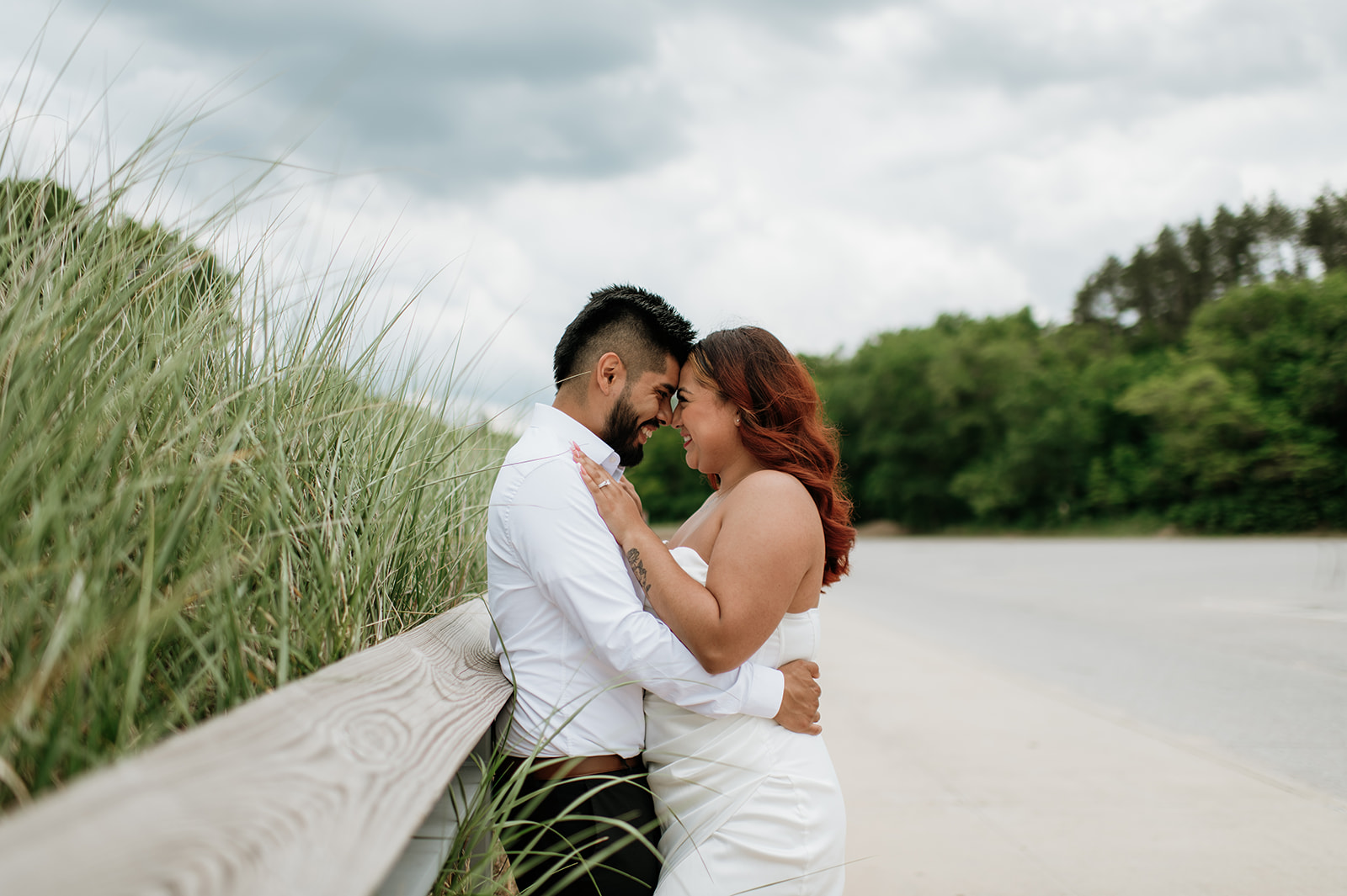 Bride and groom leaning against a fence for portraits