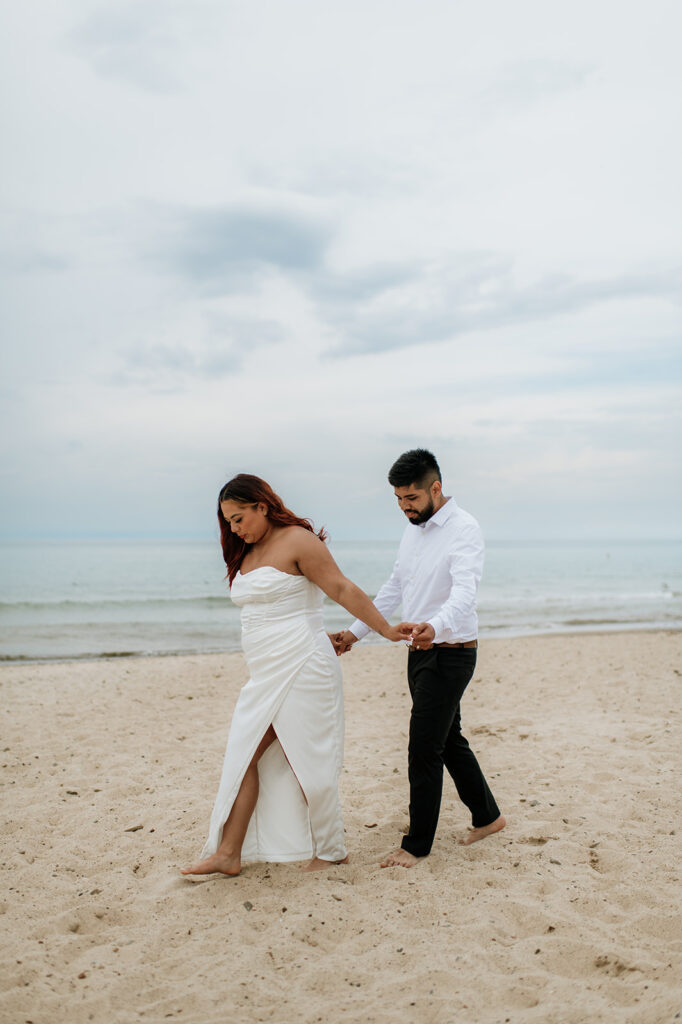 Bride and groom holding hands as they walk on the beach for their elopement in Indiana at Indiana Dunes National Park