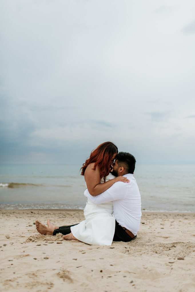 Bride straddling her groom on the beach during their intimate summer elopement