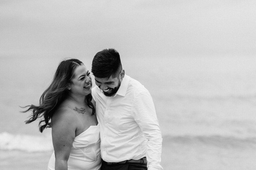 Black and white photo of a bride and groom on the beach