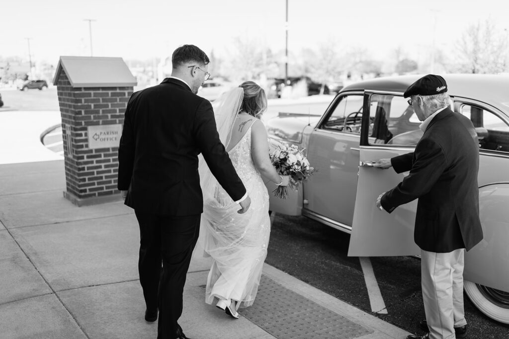 Black and white photo of a bride and groom getting into a 1940s original Studebaker