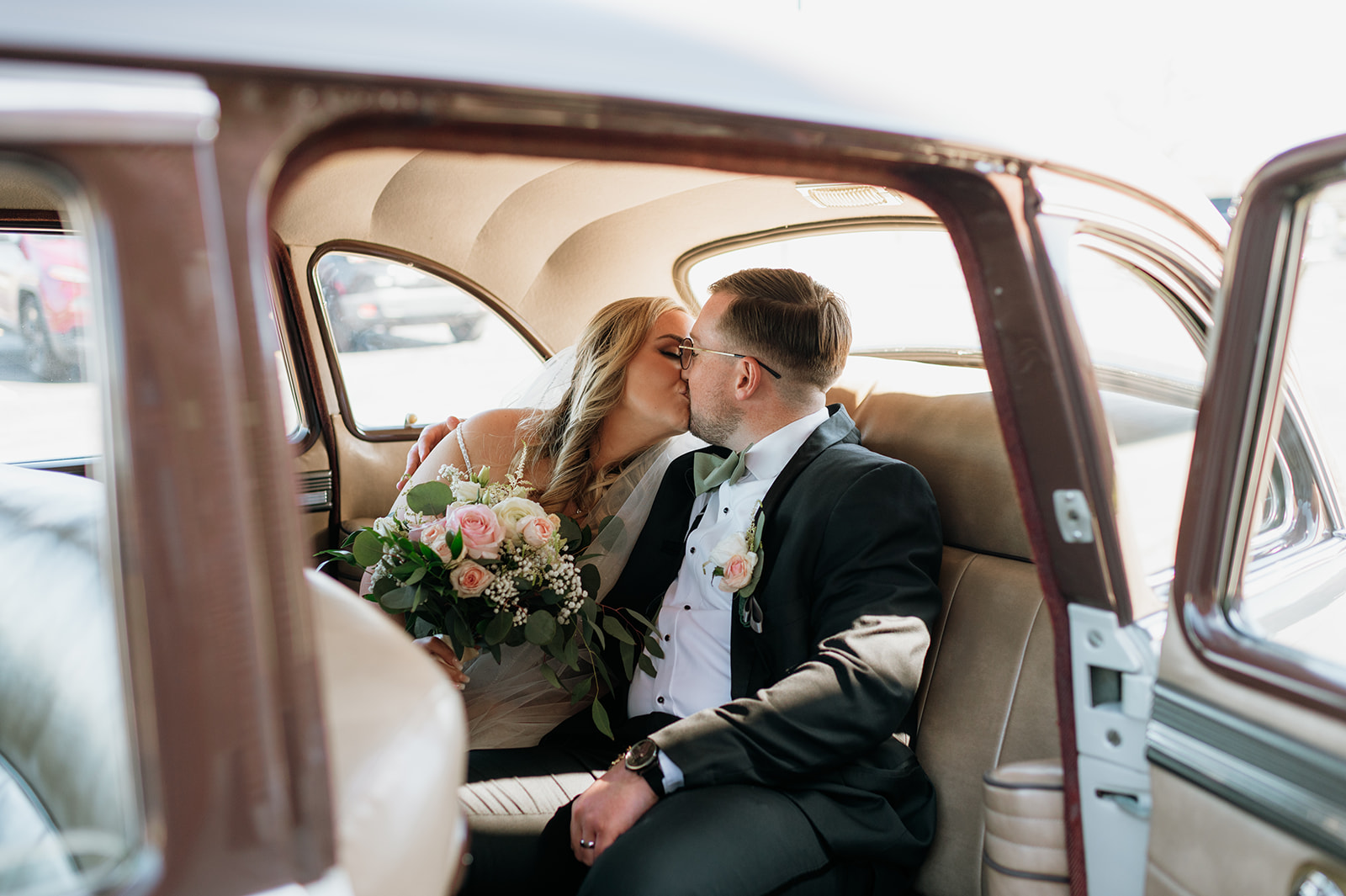 Bride and groom kissing in a 1940s original Studebaker