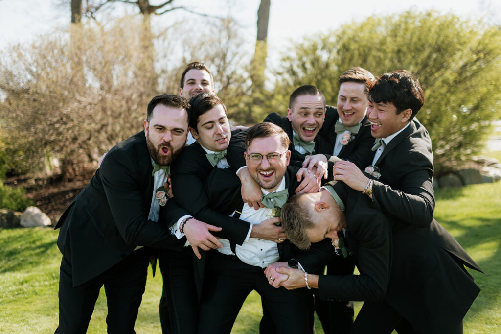 Groomsmen attacking the groom for fun wedding day photos