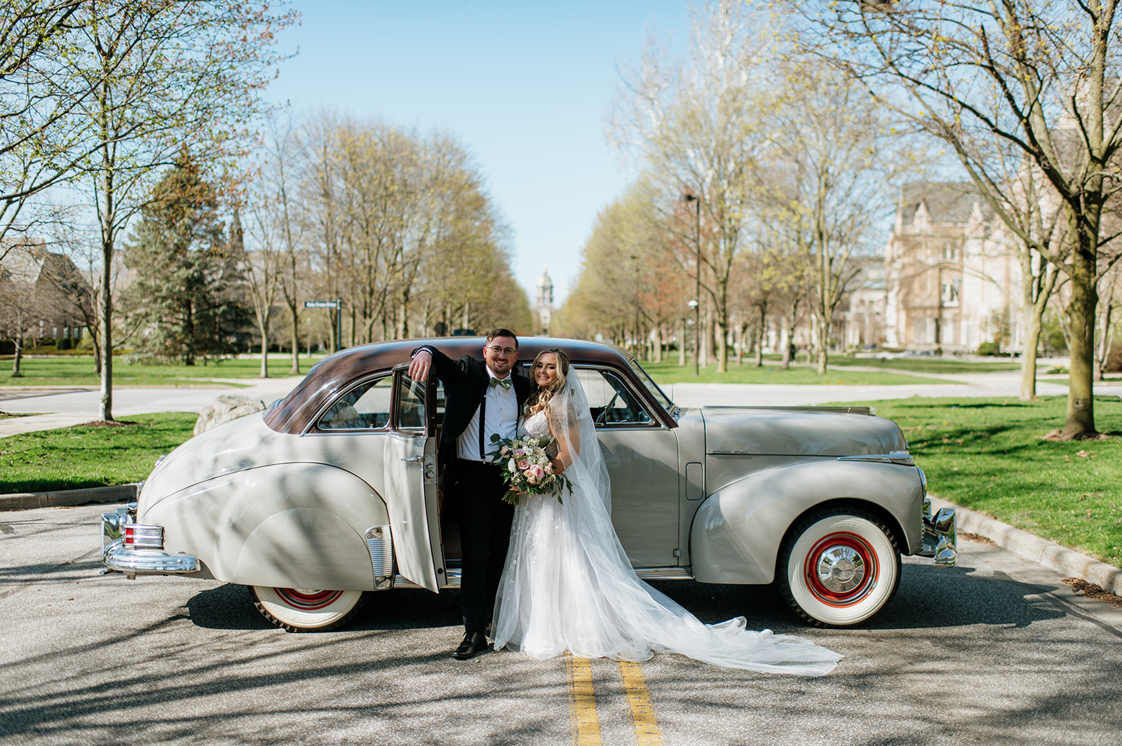 Bride and groom posing with a 1940s original Studebaker car