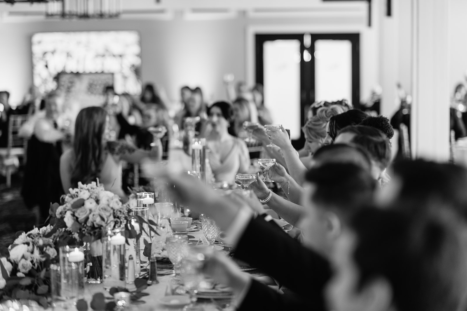 Black and white photo of wedding guests toasting during the reception