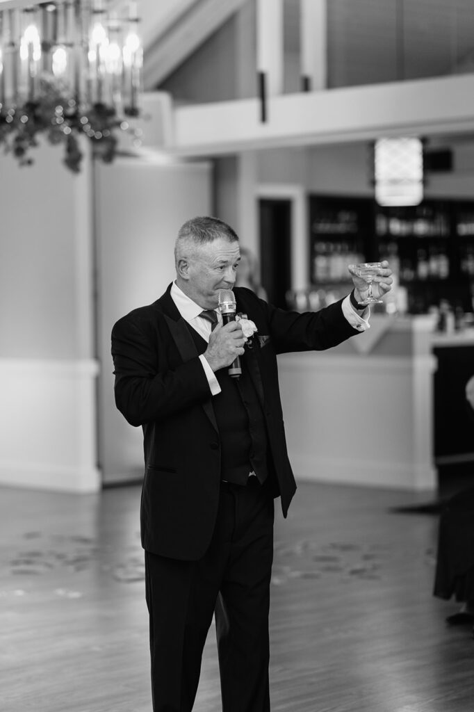 Black and white photo of the father of the bride toasting to the couple