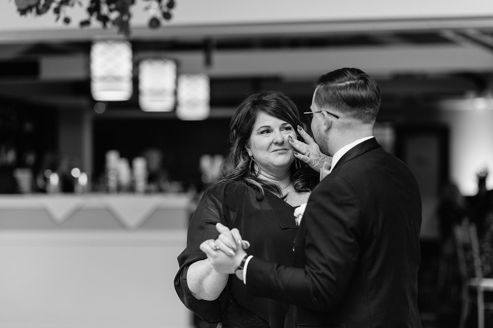 Black and white photo of a groom and his mother dancing during the reception 