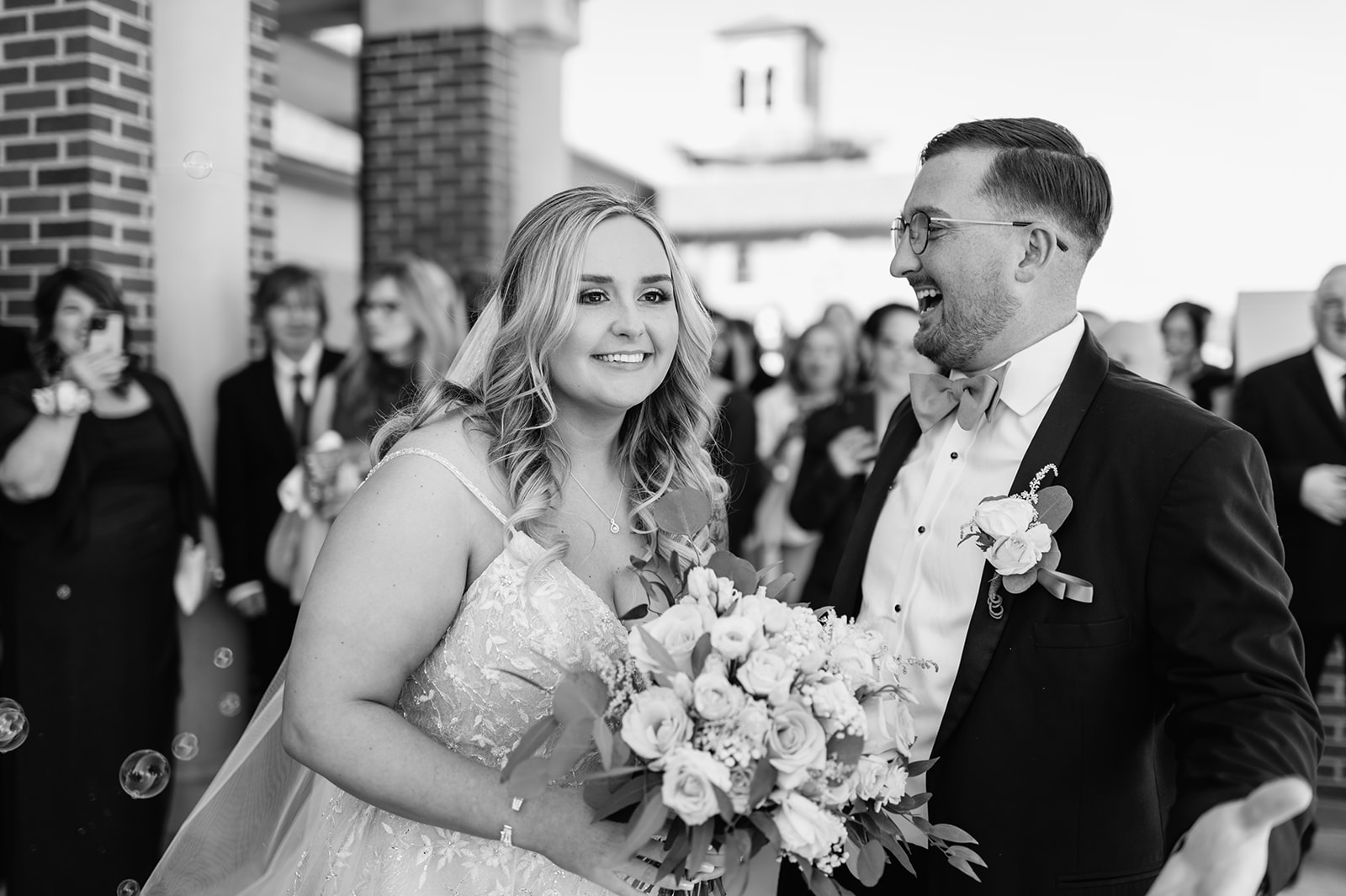 Black and white photo of a bride and groom during their bubble wedding ceremony exit