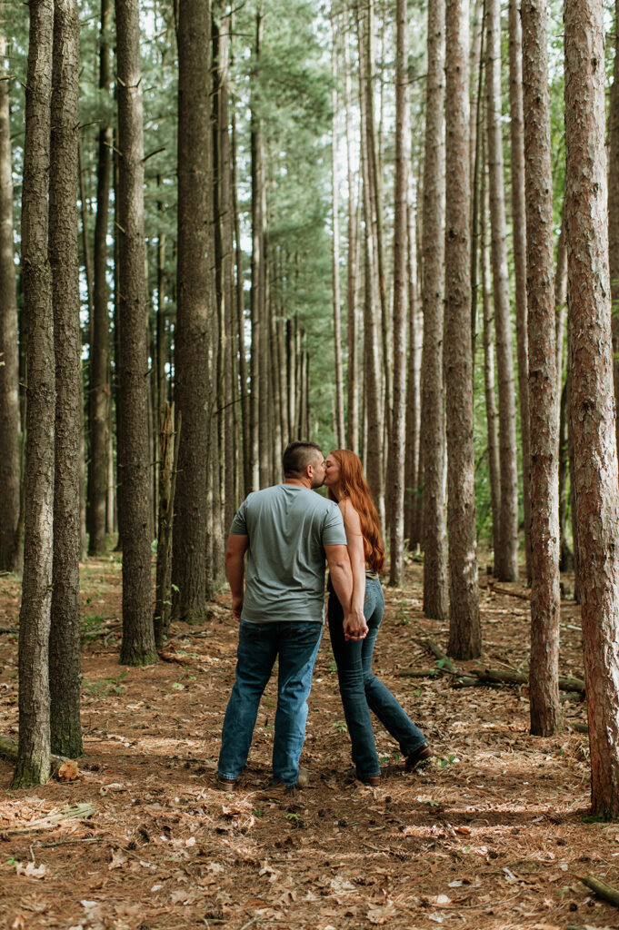 Couple kissing in the woods for their engagement photos in Indiana