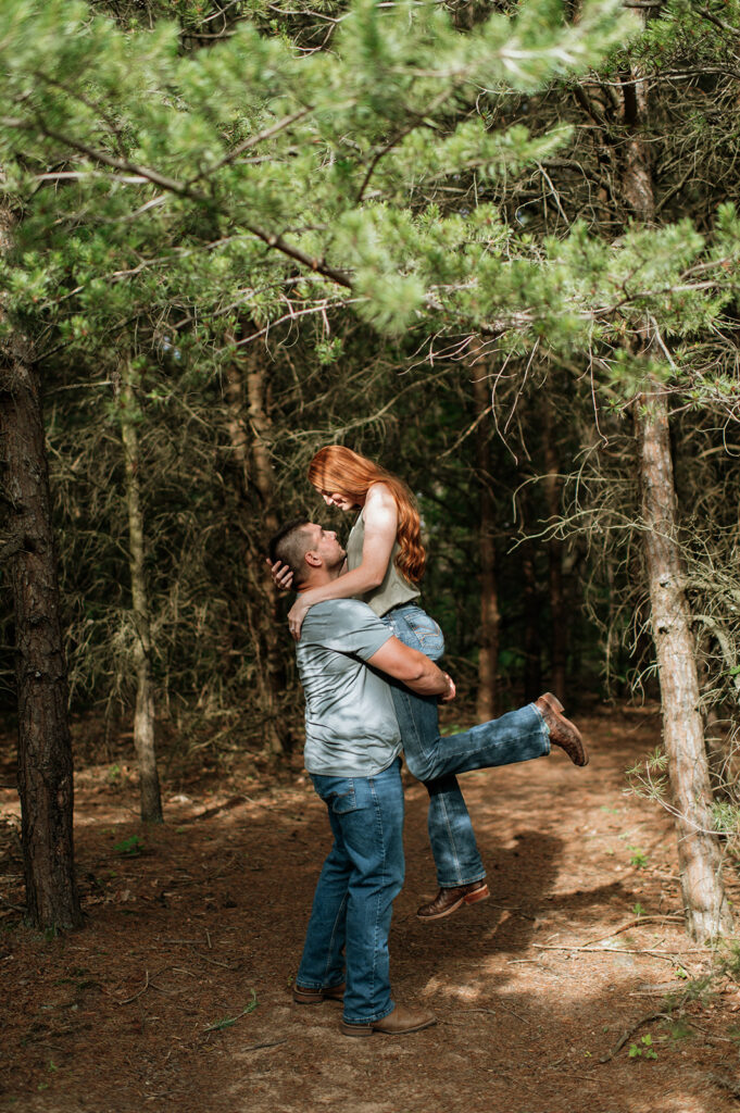 Man lifting woman up during their photoshoot in the woods