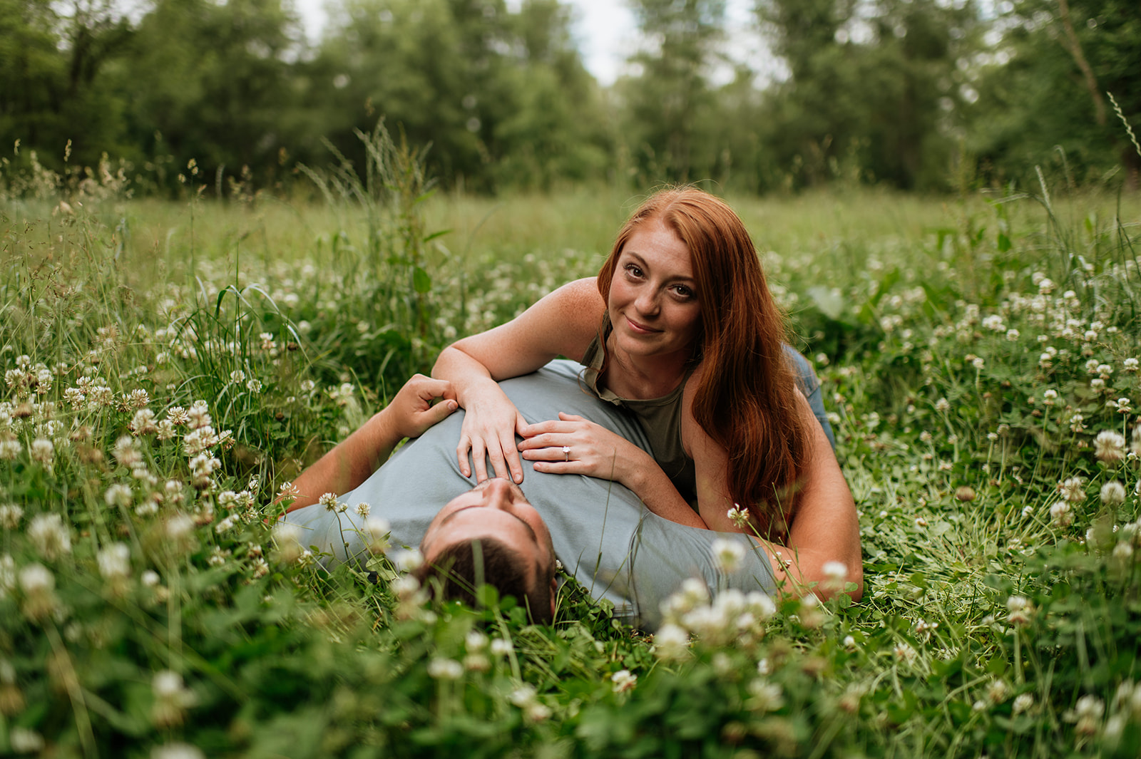 Couple laying in a field of wildflowers during their outdoor summer engagement photos in Indiana