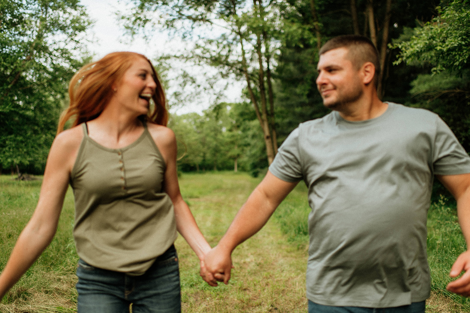 Couple holding hands and running through an open field