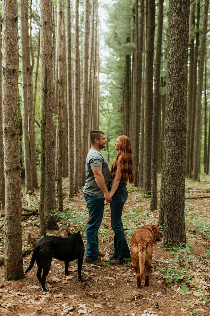 Couple holding hands in the woods for their outdoor summer engagement photos in Indiana