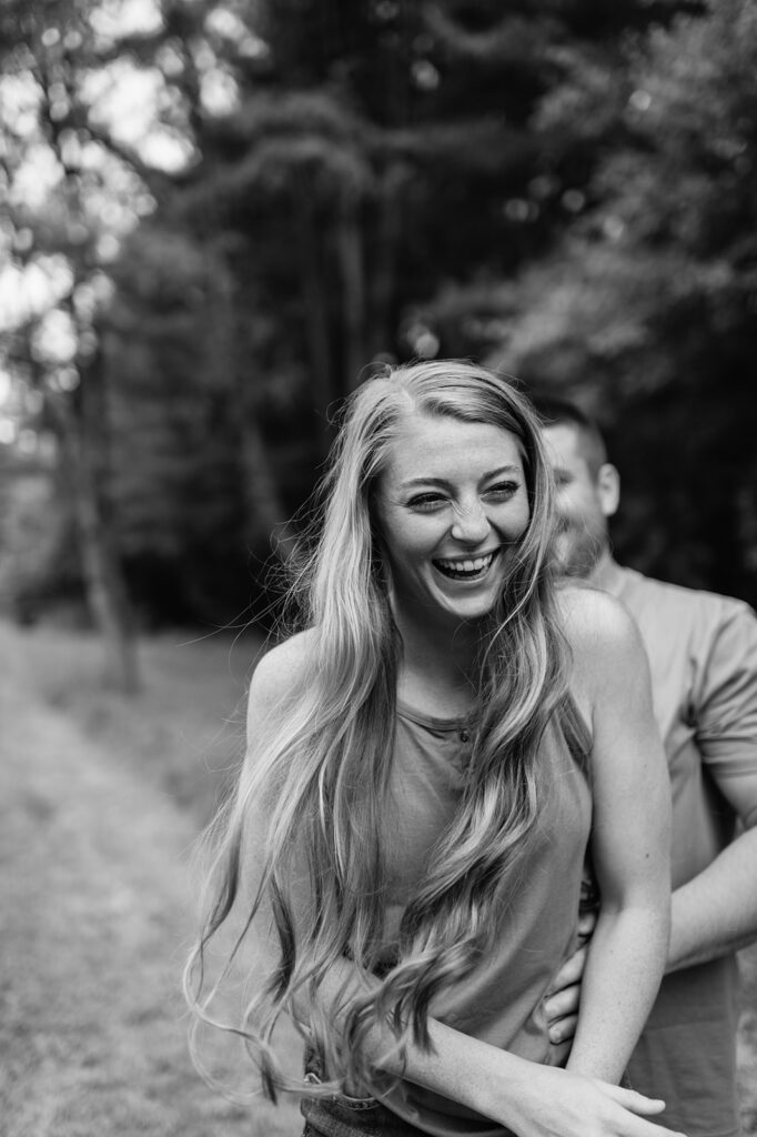 Black and white photo of a woman laughing during her engagement photoshoot