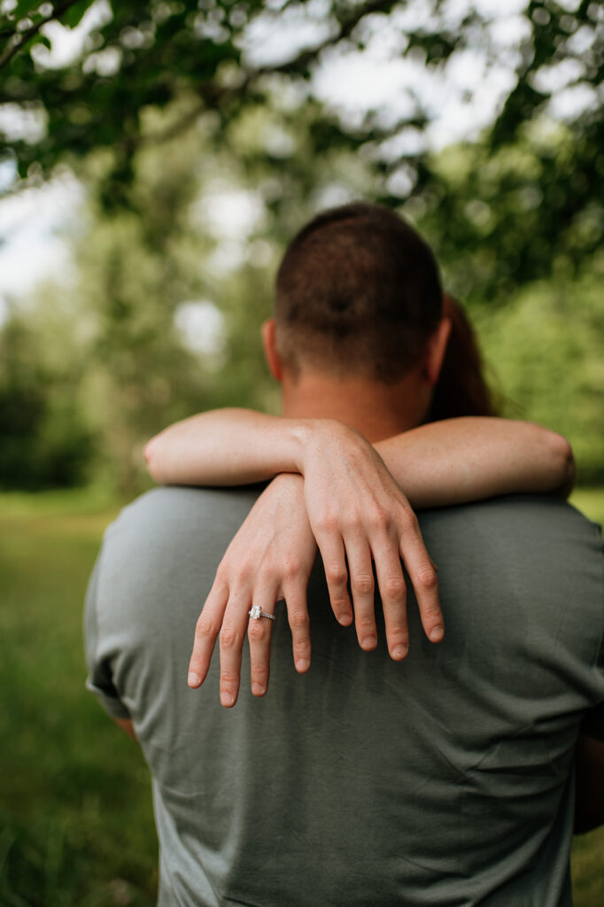 Woman with her arms wrapped around her fiancé showing off her ring