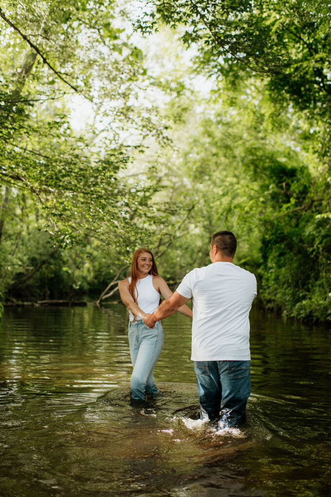 Man and woman being playful in a creek on their property 