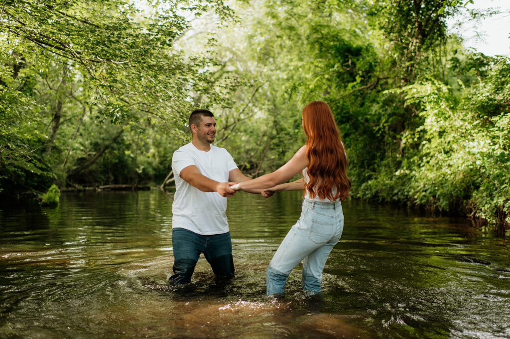 Man and woman holding hands and being playful in a creek