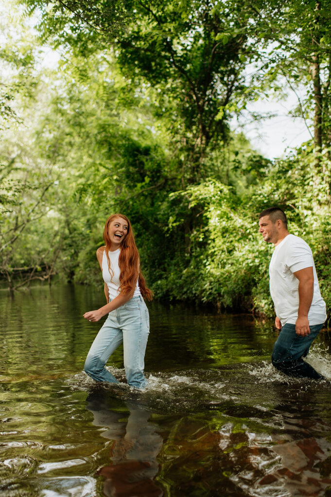 Man and woman walking through a creek for their outdoor engagement photos in Indiana