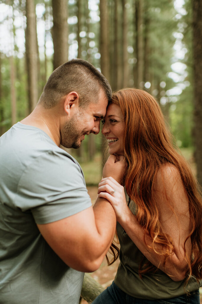 Man holding his fiancés chin during their outdoor summer engagement photos in Indiana