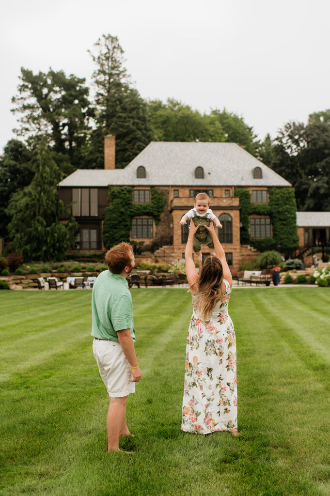 Mother throwing her baby up in the air playfully during their Lake Michigan family photos at their lake home in Holland